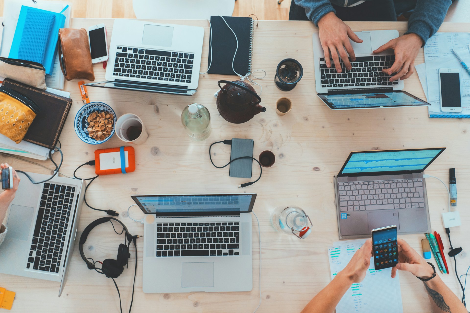 an overlook of laptops & gadgets on a wooden table from above